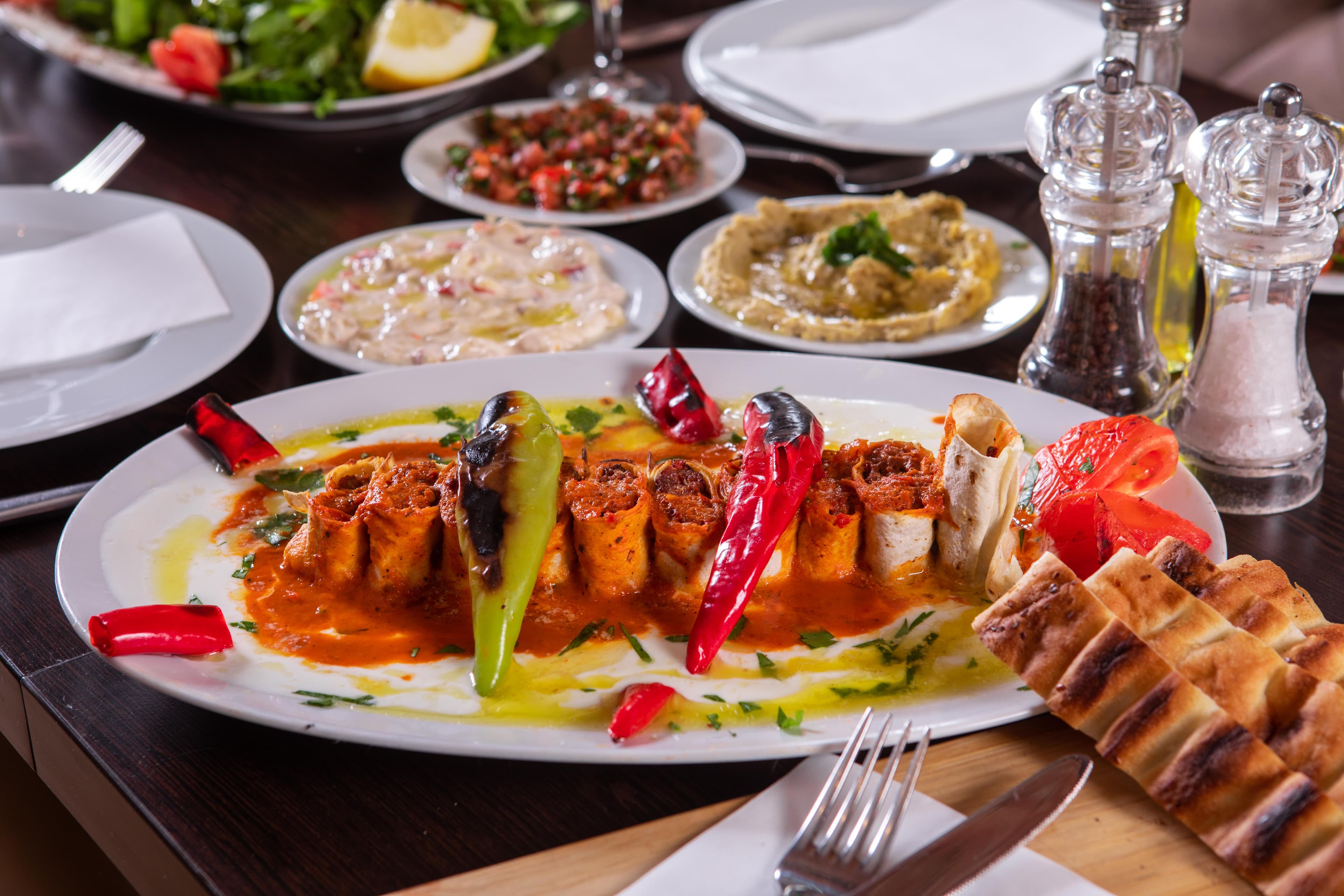Mezze-Auswahl mit Salat, Hummus, Baba Ganoush und gefüllten Teigröllchen